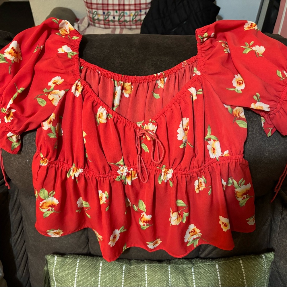 Red blouse with flowers on it. Flowy and a bit cropped.